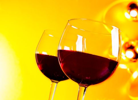 two red wine glasses against golden lights background, festive and fun concept