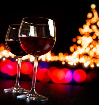 two red wine glass against bokeh lights tree background, christmas atmosphere