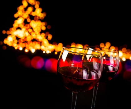 red wine glass against bokeh lights background, christmas atmosphere