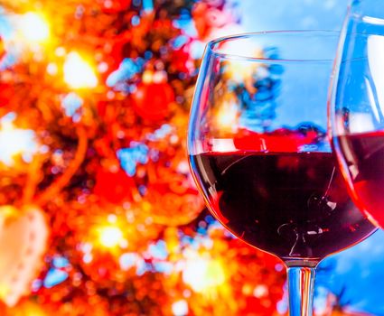 red wine glass against blur lights tree background, christmas atmosphere