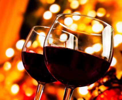two red wine glasses against tree of bokeh lights background, christmas atmosphere