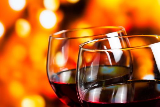 two red wine glasses against colorful unfocused lights background, festive and fun concept