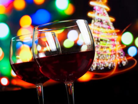 red wine glass against bokeh lights tree background, christmas atmosphere