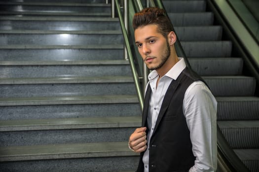 Profile shot of handsome young man inside train station looking at camera