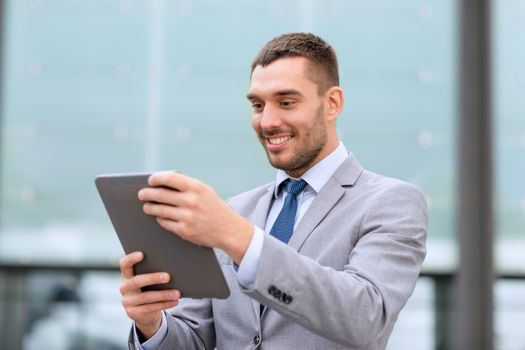 business, education, technology and people concept - smiling businessman working with tablet pc computer on city street