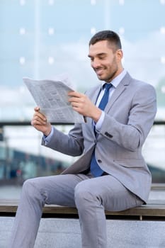 business, hot drinks and people and concept - young smiling businessman with newspaper over office building