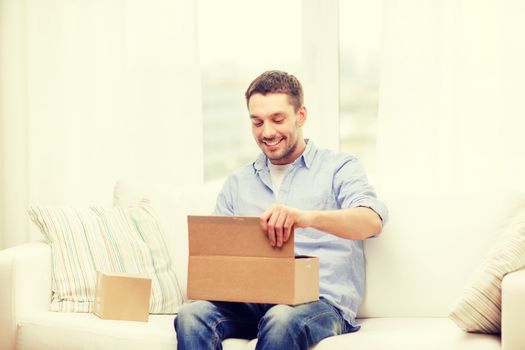 post, home and lifestyle concept - smiling man with cardboard boxes at home