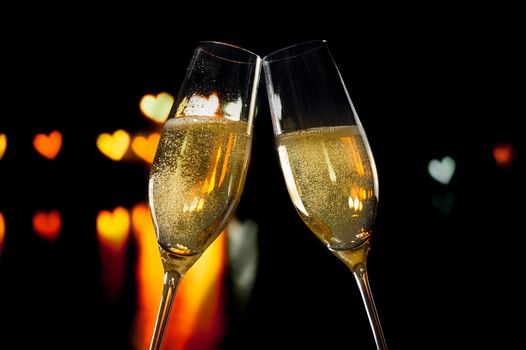 champagne flutes with golden bubbles make cheers on hearts bokeh background valentine day concept