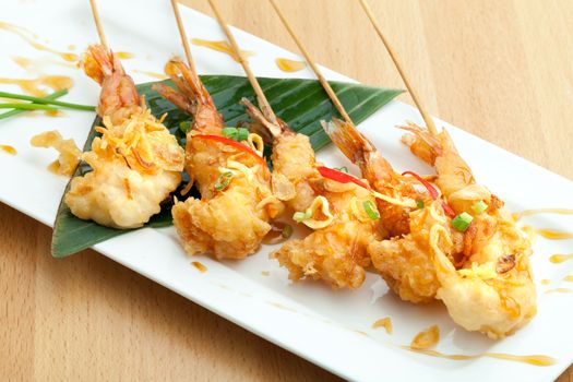 Tempura jumbo shrimp skewers on a white plate.