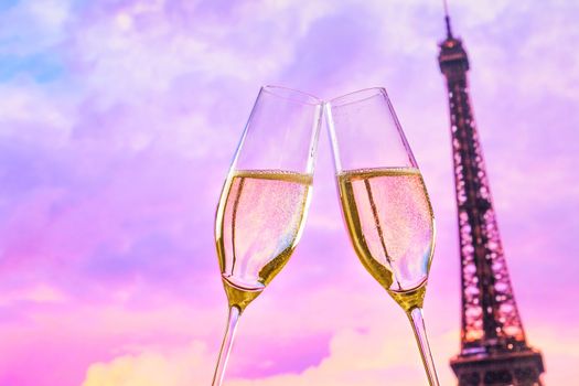 a pair of champagne flutes with golden bubbles make cheers on sunset blur tower Eiffel background valentine day concept