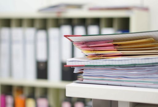 Document report and file work stacked on table at office.                            