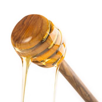 Honey dripping from honey drizzle stick, isolated on a white background.