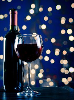 red wine glass near bottle with light blue bokeh in background