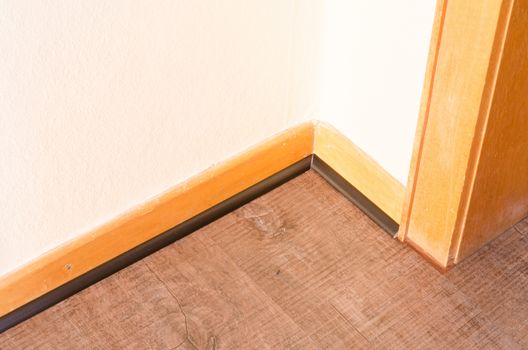 Installation of a wood baseboard at the bottom of a wall after installing flooring.