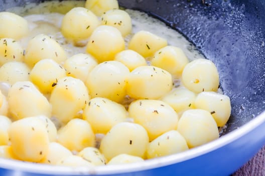 Baked potatoes in frying pan seasoned with rosemary.