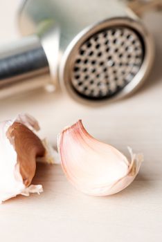 Garlic and garlic press on wooden table