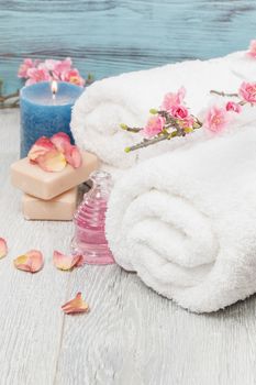Spa and wellness setting with rose petals, natural soap, candle and towel.Macro photograph with shallow depth of field.