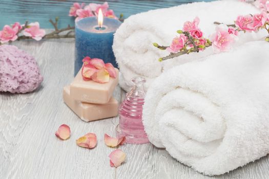 Spa and wellness setting with rose petals, natural soap, candle and towel.Macro photograph with shallow depth of field.