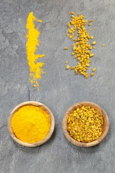 Top angle view of turmeric in olive wood bowls, presented In various forms, pieces and ground. Macro, selective focus