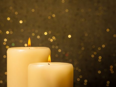 candles with flame on golden bokeh background and space for text