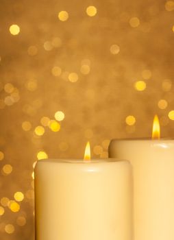 candles with flame on golden bokeh background and space for text