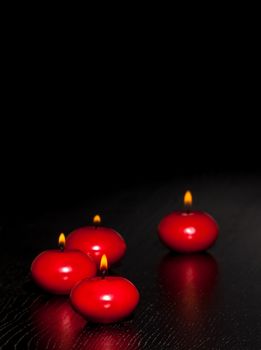 red candles with flame on wood and black background and space for text
