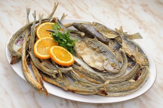 dish with various fried fish with slice of orange