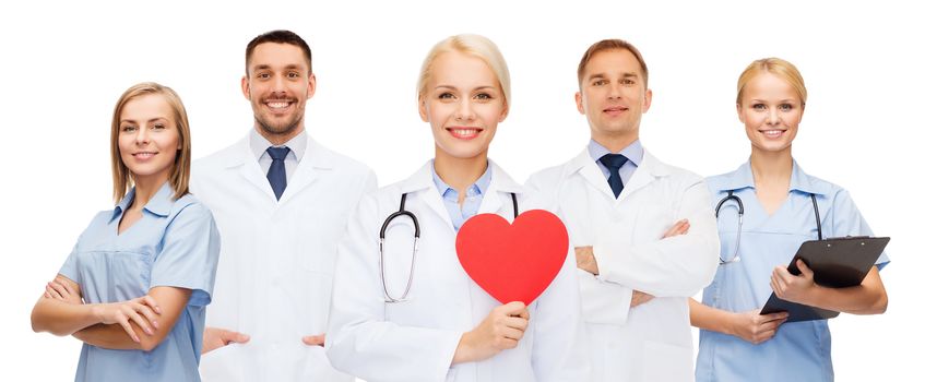 medicine, profession, teamwork and healthcare concept - group of smiling medics or doctors holding red paper heart shape, clipboard and stethoscopes over white background