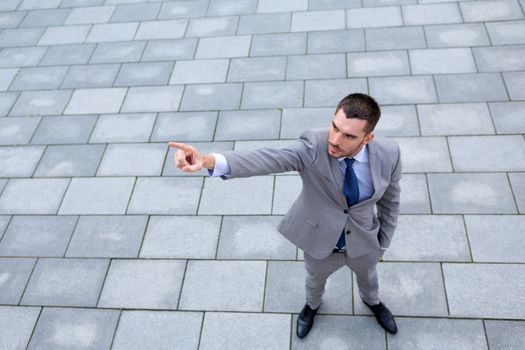 business, development and people and concept - young smiling businessman pointing finger outdoors from top