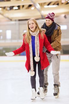 people, friendship, sport and leisure concept - happy couple on skating rink