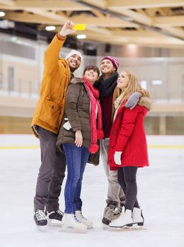 people, friendship, technology and leisure concept - happy friends taking selfie with smartphone on skating rink