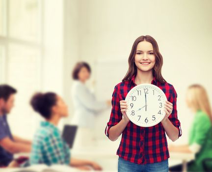 happiness and people concept - smiling young woman in casual clothes with wall clock showing 8 oclock