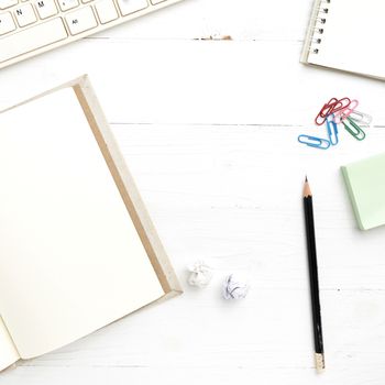 computer and notebook with office supplies over white table