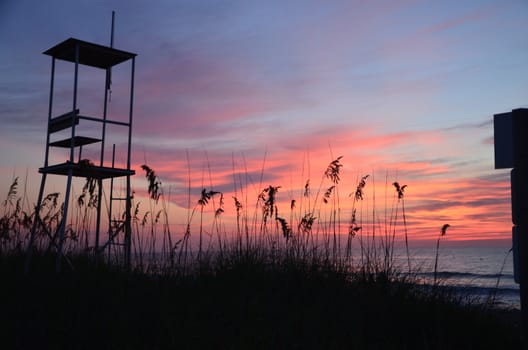 Sunrise at Kure Beach North Carolina on a warm summer morning. An empty lifegaurd stand is shown as well.