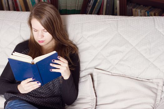 young woman reading a book on the couch