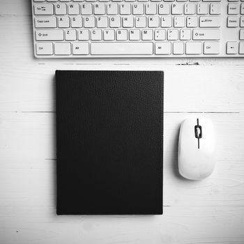 computer and brown notebook with office supplies on white table black and white style