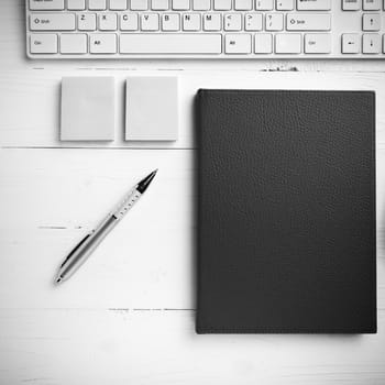 computer and brown notebook with office supplies on white table black and white style