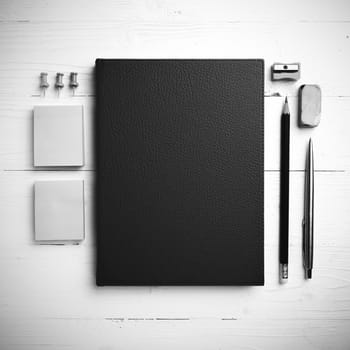 brown notebook with office supplies on white table view from above black and white style