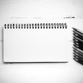 notepad with color pencil on white table view from above black and white color style