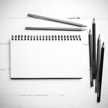 notepad with color pencil on white table view from above black and white color style