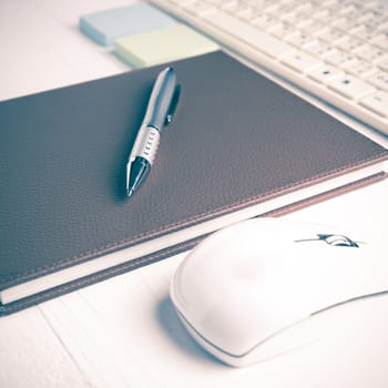 computer and brown notebook with office supplies on white table vintage style