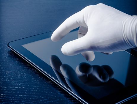 hand in medical glove touching modern digital tablet pc on wood table. Concept of medical or research theme