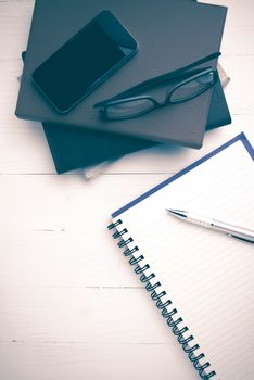 notepad with stack of book on white table view from above vintage style