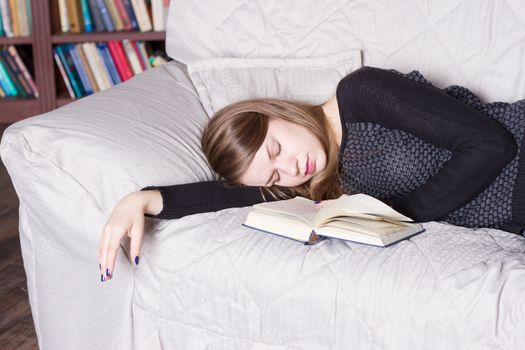 Cute girl sleeping while holding a book lying on her bed