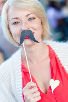 Portrait of girl wearing fake mustache: symbol of Movember, annual, month-long event involving the growing of moustaches during the month of November to raise awareness of men's health issues.