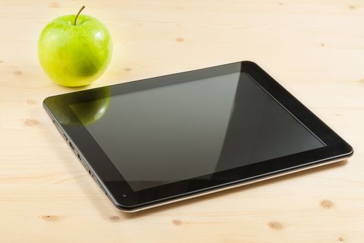 digital tablet pc near green apple on wood table, concept of learn new technology