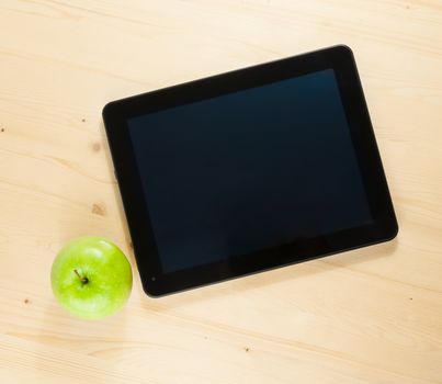 top of view of digital tablet pc and green apple on wood table, concept of learn new technology