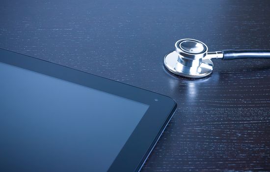 medical stethoscope on modern digital tablet pc on wood table. Concept of new technology for research