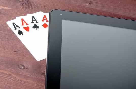 detail of poker cards on digital tablet pc on old wood table, concept of  texas poker online