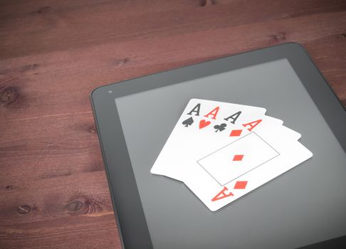 poker cards on digital tablet pc on old wood table, concept of  texas poker online